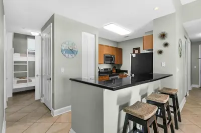 a kitchen with a black counter and stools at Aqua 0111 in Panama City Beach