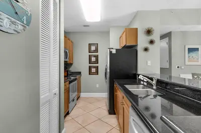 a kitchen with a black refrigerator and wooden cabinets at Aqua 0111 in Panama City Beach