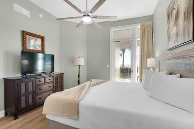 a bedroom with a large bed and a flat screen tv at Aqua 0111 in Panama City Beach