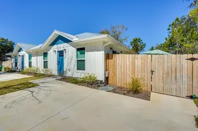a white house with a wooden fence at 1 Mi to Beach Dog-Friendly PCB Home with Backyard! in Panama City Beach