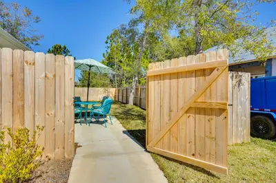 a wooden fence with a gate in a yard with a table at 1 Mi to Beach Dog-Friendly PCB Home with Backyard! in Panama City Beach