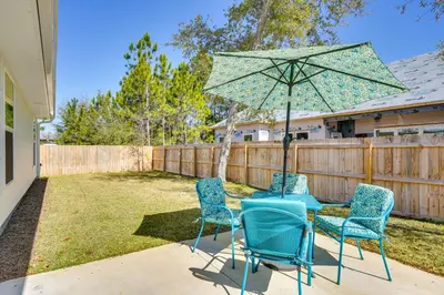 a patio with two chairs and a table with an umbrella at 1 Mi to Beach Dog-Friendly PCB Home with Backyard! in Panama City Beach