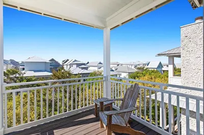 a rocking chair on a balcony with a view of the ocean at Inlet Breeze in Inlet Beach