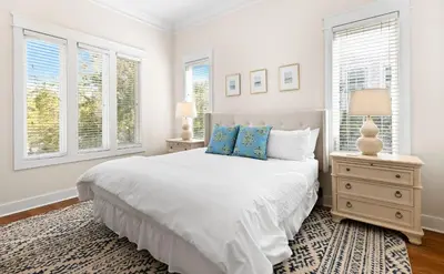 a white bedroom with a bed and two windows at Inlet Breeze in Inlet Beach