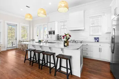 a kitchen with white cabinets and a large island with bar stools at Inlet Breeze in Inlet Beach