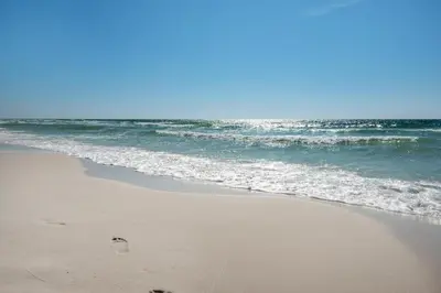 a sandy beach with the ocean and waves at Dune Villas 6A in Santa Rosa Beach