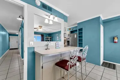 a kitchen with blue walls and a sink and two chairs at The Summit 1209 in Panama City Beach
