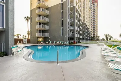 a swimming pool with chairs and a building at Panama City Condo Rental Studio with Private Beach Access in Panama City Beach
