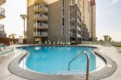 a swimming pool with chairs and a building at Panama City Condo Rental Studio with Private Beach Access in Panama City Beach