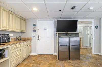 a kitchen with a refrigerator and a flat screen tv at Panama City Condo Rental Studio with Private Beach Access in Panama City Beach