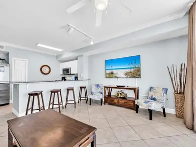 a kitchen and living room with a table and chairs at Tidewater 716 in Panama City Beach