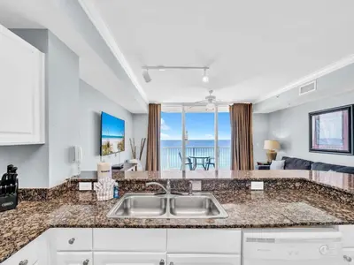 a kitchen and living room with a view of the ocean at Tidewater 716 in Panama City Beach