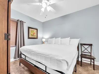 a bedroom with a white bed with a ceiling fan at Tidewater 716 in Panama City Beach
