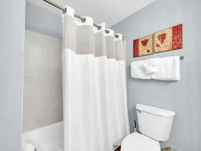 a bathroom with a white shower curtain and a toilet at Tidewater 716 in Panama City Beach