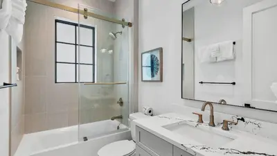 a bathroom with a sink and a toilet and a mirror at Beach Sea-kers Retreat by AvantStay Rooftop Deck w Views Pool Luxury 5BDR in Inlet Beach