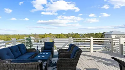 a deck with wicker chairs and tables on a balcony at Beach Sea-kers Retreat by AvantStay Rooftop Deck w Views Pool Luxury 5BDR in Inlet Beach