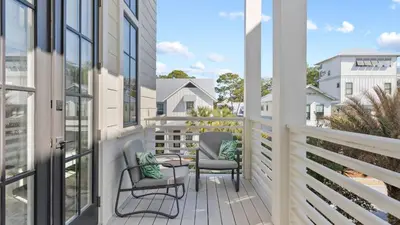 a balcony with two chairs and glass doors at Beach Sea-kers Retreat by AvantStay Rooftop Deck w Views Pool Luxury 5BDR in Inlet Beach