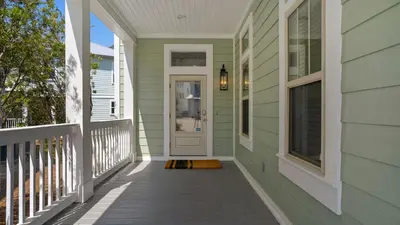 a front porch of a house with a white door at The Cake Cottage in Santa Rosa Beach