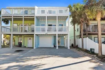 a large apartment building with palm trees in front of it at Beach House - Sunset Paradise by Panhandle Getaways in Panama City Beach
