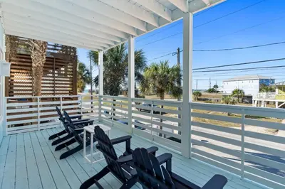a porch with chairs and a table with a view of the beach at Beach House - Sunset Paradise by Panhandle Getaways in Panama City Beach