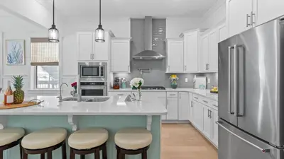 a kitchen with white cabinets and a large island with bar stools at Resorting To Happiness by AvantStay Close to the Beach w Pool Access in Inlet Beach