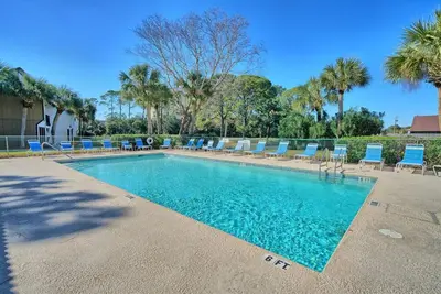 a swimming pool with blue chairs and palm trees at Edgewater Beach Resort Dream Villa! One Bedroom in Panama City Beach