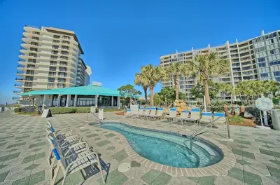 a swimming pool with chairs and a large building at Edgewater Beach Resort Dream Villa! One Bedroom in Panama City Beach