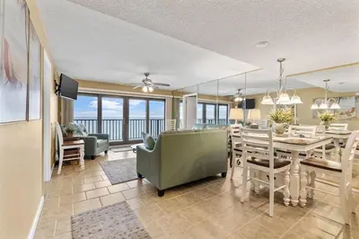 a dining room and living room with a table and chairs at Commodore 1205 with 2 beachfront masters in Panama City Beach