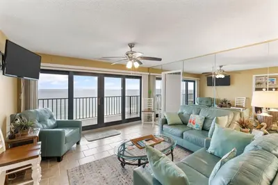 a living room with blue couches and a balcony at Commodore 1205 with 2 beachfront masters in Panama City Beach
