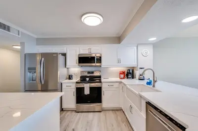 a kitchen with white cabinets and stainless steel appliances at Dunes of Panama 1506 in Panama City Beach