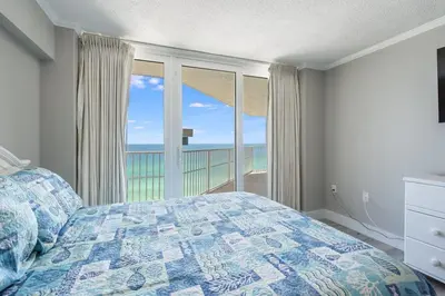 a bedroom with a bed and a view of the ocean at Dunes of Panama 1506 in Panama City Beach