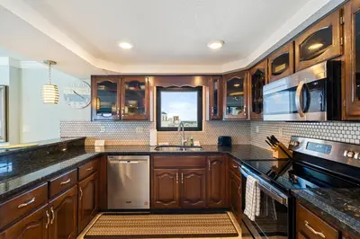 a kitchen with wooden cabinets and a sink and a window at Watercrest 1710 - Sunsets in Paradise - Sleeps 8 in Panama City Beach