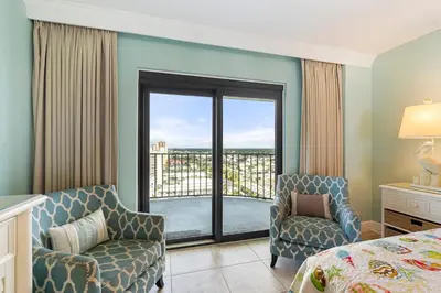 a bedroom with a bed and chairs and a balcony at Watercrest 1710 - Sunsets in Paradise - Sleeps 8 in Panama City Beach