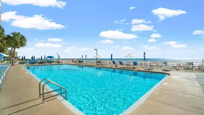 a swimming pool at the beach with chairs and umbrellas at Regency Towers 1018 Beachfront unit in Panama City Beach