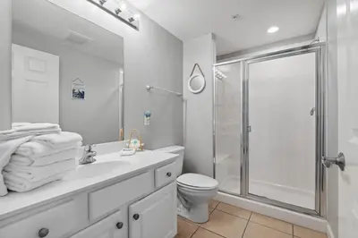 a white bathroom with a shower and a toilet at Seychelles 1406 Free Beach Chairs in Panama City Beach