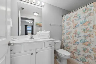 a bathroom with a toilet and a sink and a shower curtain at Seychelles 1406 Free Beach Chairs in Panama City Beach