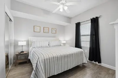a white bedroom with a bed and a ceiling fan at Seychelles 1406 Free Beach Chairs in Panama City Beach
