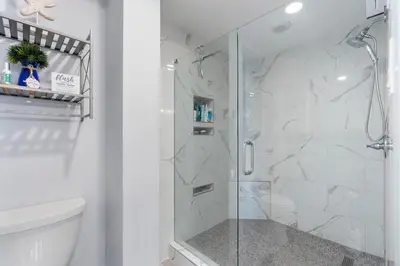 a bathroom with a shower with a glass door at Edgewater Windward 508 - Newly Renovated Corner Condominium! in Panama City Beach