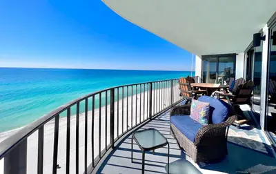 a balcony with chairs and a table and the ocean at Watercrest 1403 - Stunning Ocean Overlook in Panama City Beach
