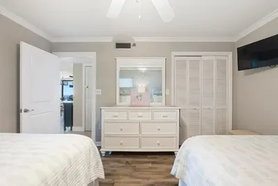 a bedroom with two beds and a dresser with a mirror at Watercrest 1403 - Stunning Ocean Overlook in Panama City Beach