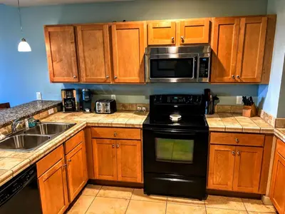 a kitchen with wooden cabinets and a black stove top oven at Origin Unit 911 in Panama City Beach
