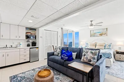a living room with a couch and a kitchen and a bed at Coastal Hideaway: Cozy Beachfront Studio – Sleeps 4 with Stunning Views! in Panama City Beach