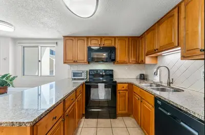 a kitchen with wooden cabinets and a black stove top oven at Serenity Found at A-521 in Panama City Beach