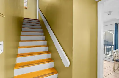 a staircase in a home with a yellow wall at Serenity Found at A-521 in Panama City Beach