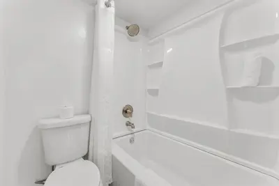 a white bathroom with a toilet and a bath tub at Serenity Found at A-521 in Panama City Beach
