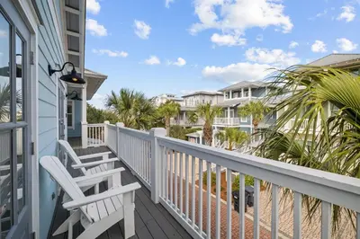 a balcony with two white chairs and palm trees at Ocean Ayer Carriage House by 30A Escapes in Rosemary Beach