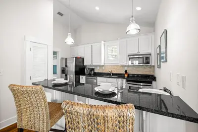a kitchen with white cabinets and a black counter top at Ocean Ayer Carriage House by 30A Escapes in Rosemary Beach
