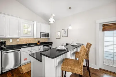 a kitchen with white cabinets and a black counter top at Ocean Ayer Carriage House by 30A Escapes in Rosemary Beach