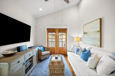 a living room with a white couch and a flat screen tv at Ocean Ayer Carriage House by 30A Escapes in Rosemary Beach