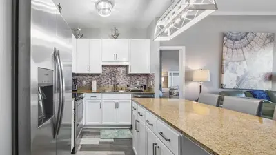 a kitchen with white cabinets and a stainless steel refrigerator at Penthouse at Laketown Wharf in PCB! 2132 in Panama City Beach